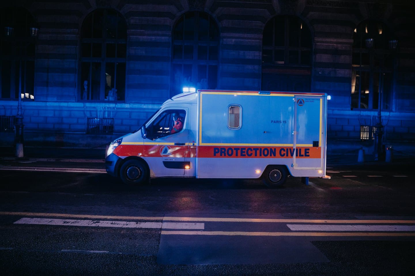 Furgoneta de servicios de emergencia con luces intermitentes en una calle mojada.