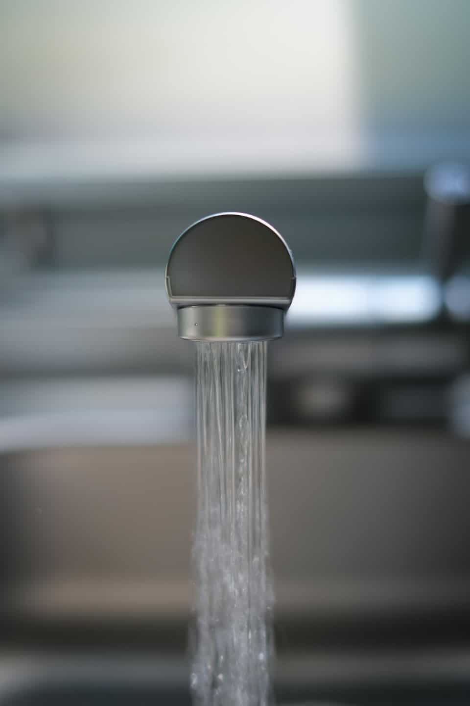 Grifo de cocina cromado con un chorro de agua clara.