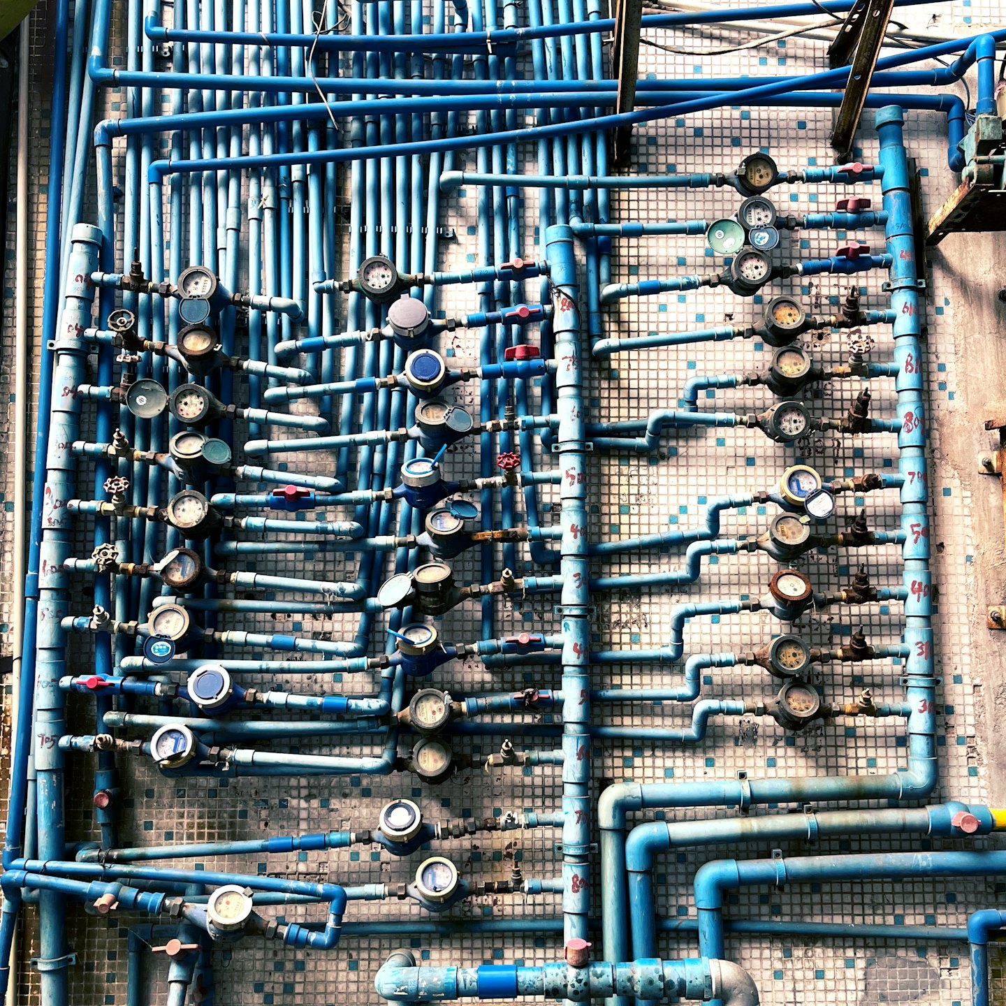 Tuberías y válvulas industriales azules cubren una pared alicatada.